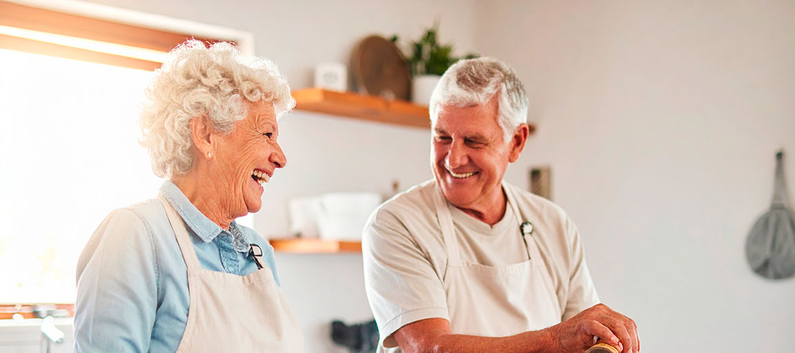 Elder couple cooking happily in their bright kitchen